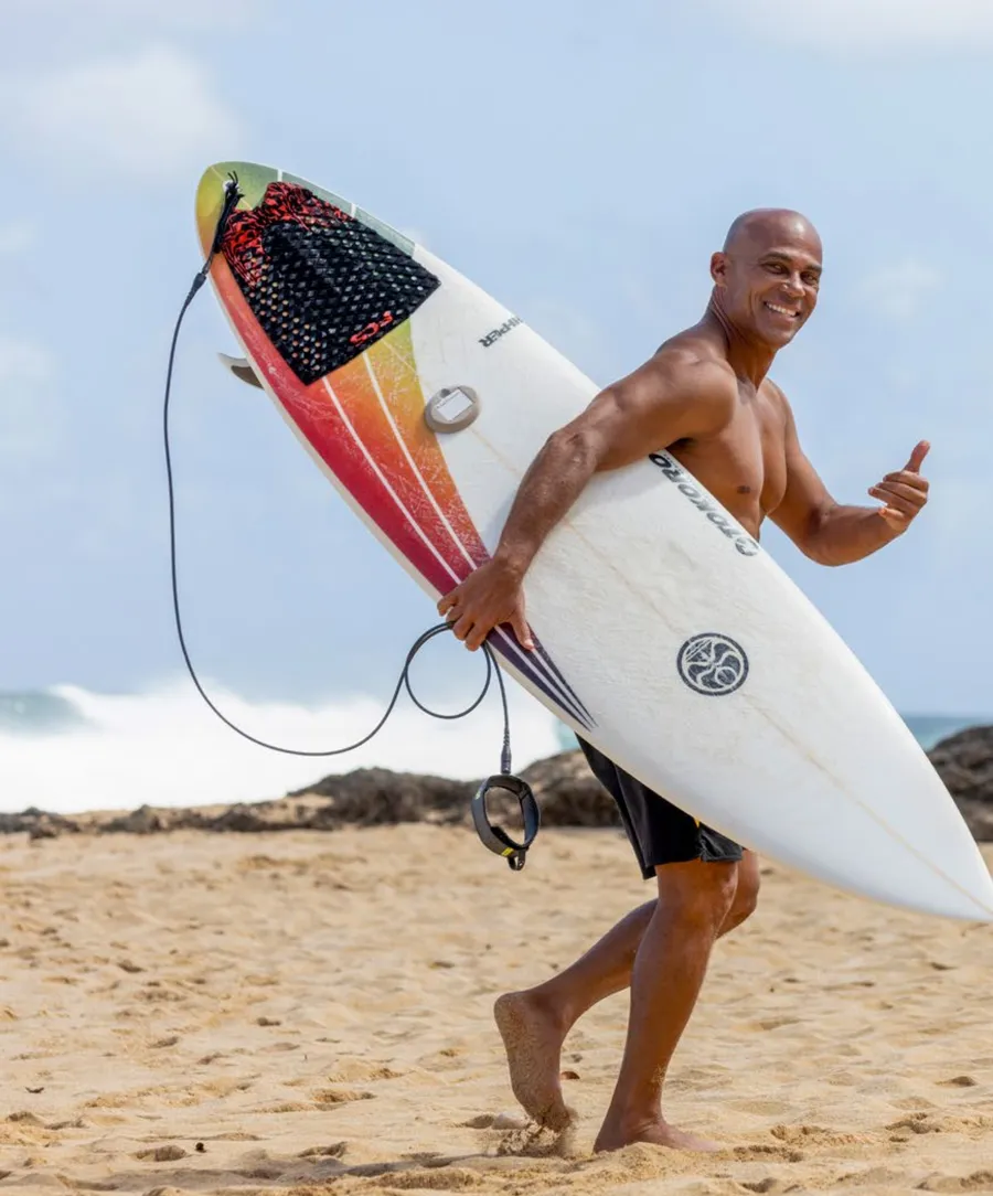 Rainos Hayes carrying his surfboard on the North Shore, from the Freesurf Magazine feature